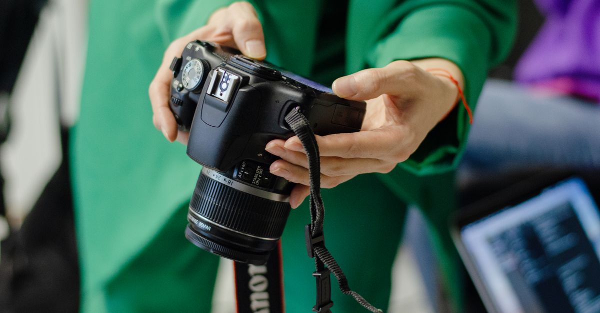 A close view of hands holding a DSLR camera, perfect for photography themes.
