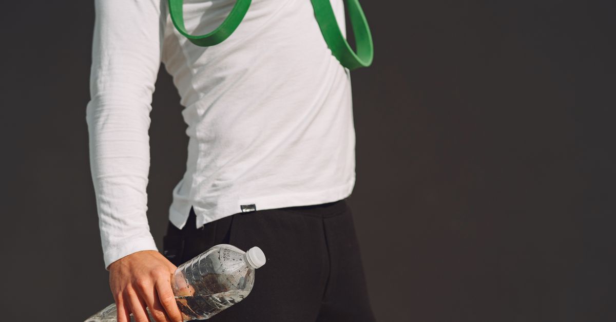 An individual holds a water bottle and fitness band, showcasing a healthy lifestyle and exercise readiness.