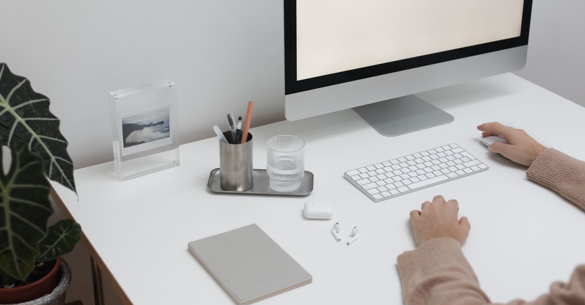 High angle of crop faceless person sitting at table with wireless gadgets and computer